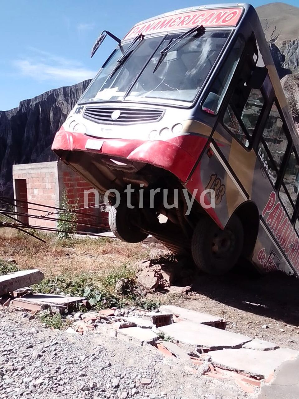 Colectivo de empresa Panamericano de Jujuy, que no cayó por quedar sobre el techo de una vivienda.